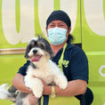 Load image into Gallery viewer, Doog expert dog groomer posing with a cute dog next to the mobile grooming van